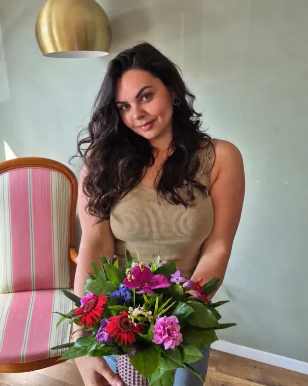 Portrait de Manon Brienne, souriante, un bouquet de fleurs à la main